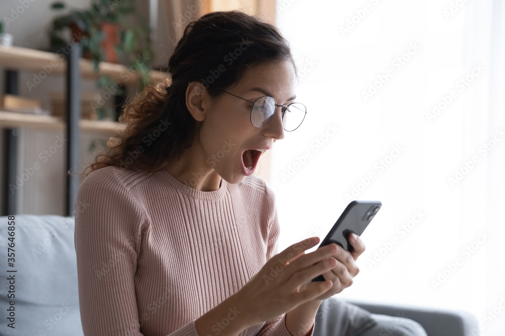 Overjoyed woman with open mouth looking at smartphone screen close up, reading unexpected message, good news, online lottery win, shocked girl wearing glasses received unbelievable shopping offer Overjoyed woman with open mouth looking at smartphone screen close up, reading unexpected message, good news, online lottery win, shocked girl wearing glasses received unbelievable shopping offer