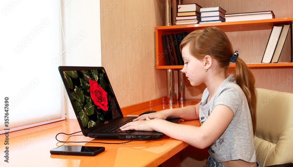 The girl is working on a laptop. Distance learning. Bedroom in the art Nouveau style. Interior of orange furniture. The girl is working on a laptop. Distance learning. Bedroom in the art Nouveau style. Interior of orange furniture.