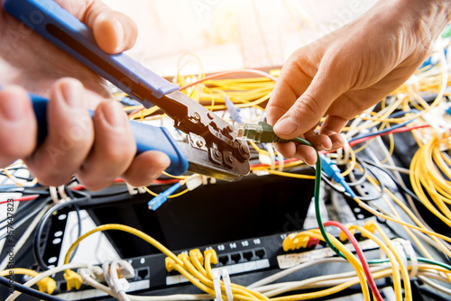 Network engineer working in server room. Connecting network cables to switches