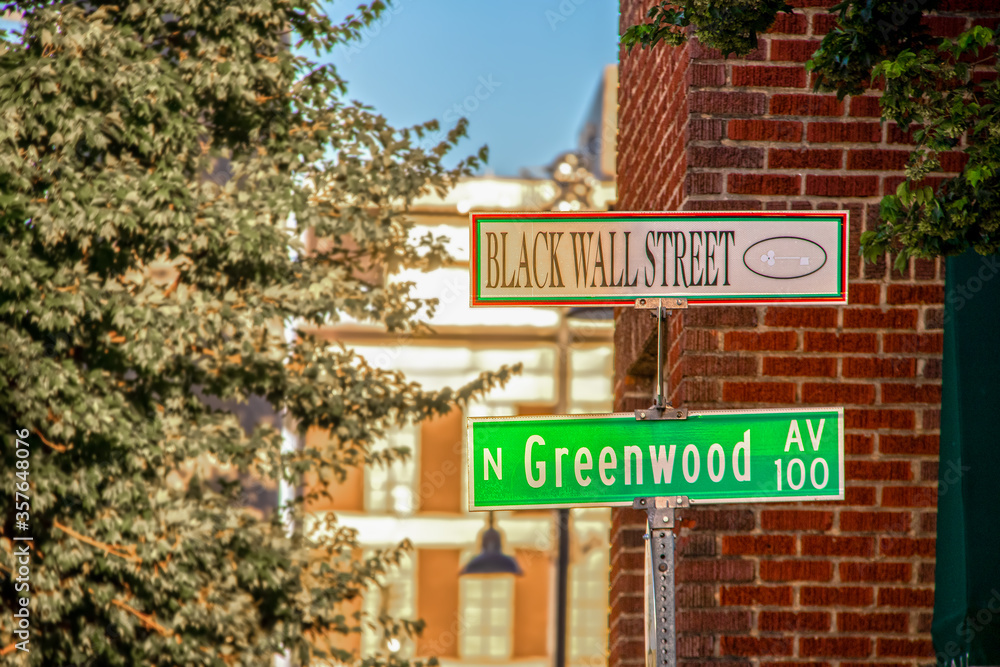 Black Wall Street and N Greenwood Avenue street signs - closeup - in Tulsa Oklahoma with bokeh background Black Wall Street and N Greenwood Avenue street signs - closeup - in Tulsa Oklahoma with bokeh background