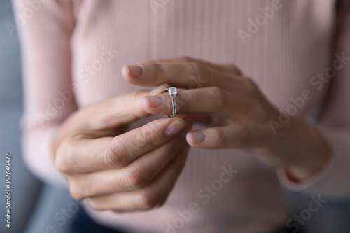 Close up young woman taking off wedding ring, divorce concept, female hands holding engagement ring, cheated girl break up with boyfriend or husband, family split, bad relationship photo