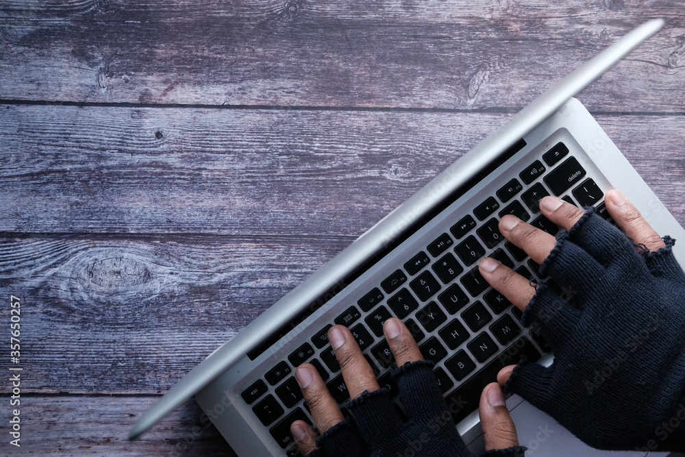 Fototapeta premium hacker hand stealing data from laptop top down