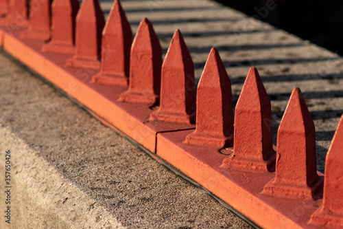 Hostile architecture. Red metal spikes on cement ledge.