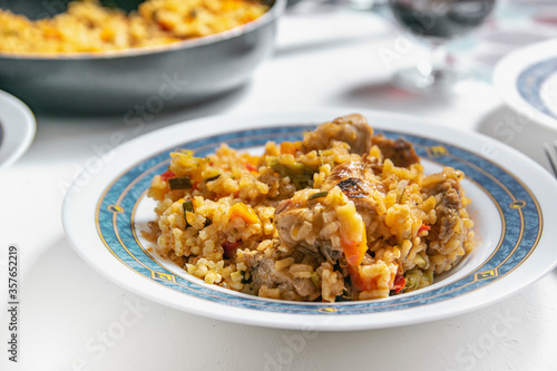 Typical Spanish rice with rabbit and vegetables recipe served on a white plate. Empty copy space for Editor's content.