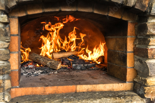 Old stone homemade pizza oven. Fire in the furnace. Homemade baking pizza. Bakery. Traditional Italian food.