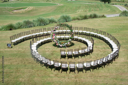 Unique round spiral chair pattern wedding ceremony setting at rolling hills countryside with brown chiavari chairs and white cushions