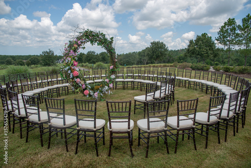 Unique round spiral chair pattern wedding ceremony setting at rolling hills countryside with brown chiavari chairs and white cushions