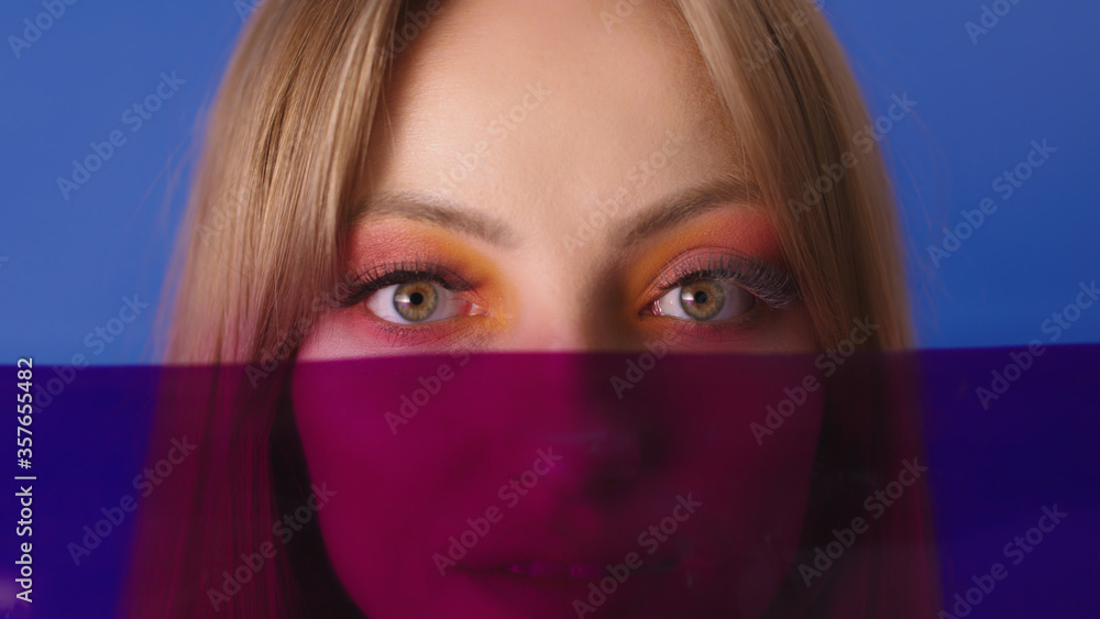 Beauty portrait shot. Young caucasian woman with make up and red film gel in front of her face. Copy space. Beauty portrait shot. Young caucasian woman with make up and red film gel in front of her face. Copy space.
