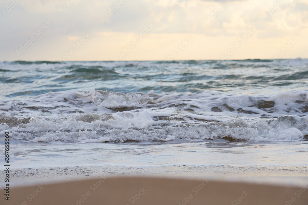 Blurred sea wave with foam on a sandy beach with horizont as a natural background/texture.