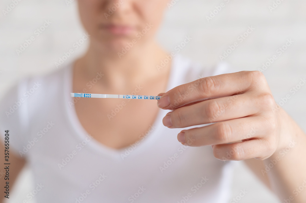 Sad woman shows a negative ovulation test. The concept of female infertility and low luteinizing hormone. Frustrated girl.