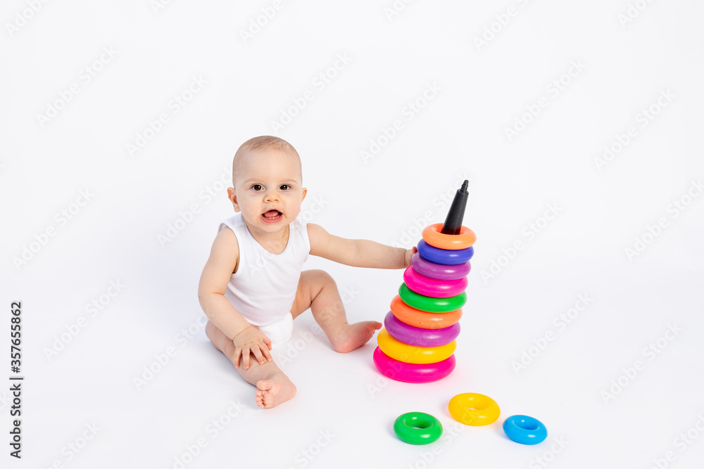 cute baby boy 8 months old playing with a pyramid on a white isolated background, place for text, early development of children cute baby boy 8 months old playing with a pyramid on a white isolated background, place for text, early development of children