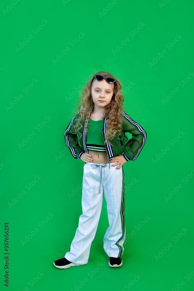 beautiful fashionable 6-year-old girl on a green isolated background with curly hair and glasses beautiful fashionable 6-year-old girl on a green isolated background with curly hair and glasses