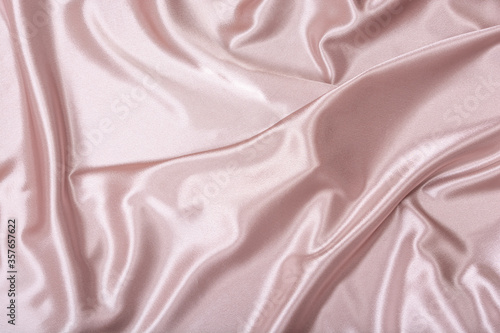 Pink satin fabric. Textile background. Powdery color. Waves and folds of fabric.