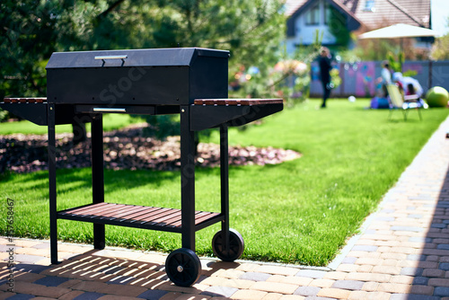 barbecue grill on wheels with wooden stands in the garden. tasty and wholesome food in the heat. future shish kebab. for holidays and events.