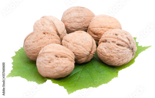 whole walnuts on green leaves isolated on white background