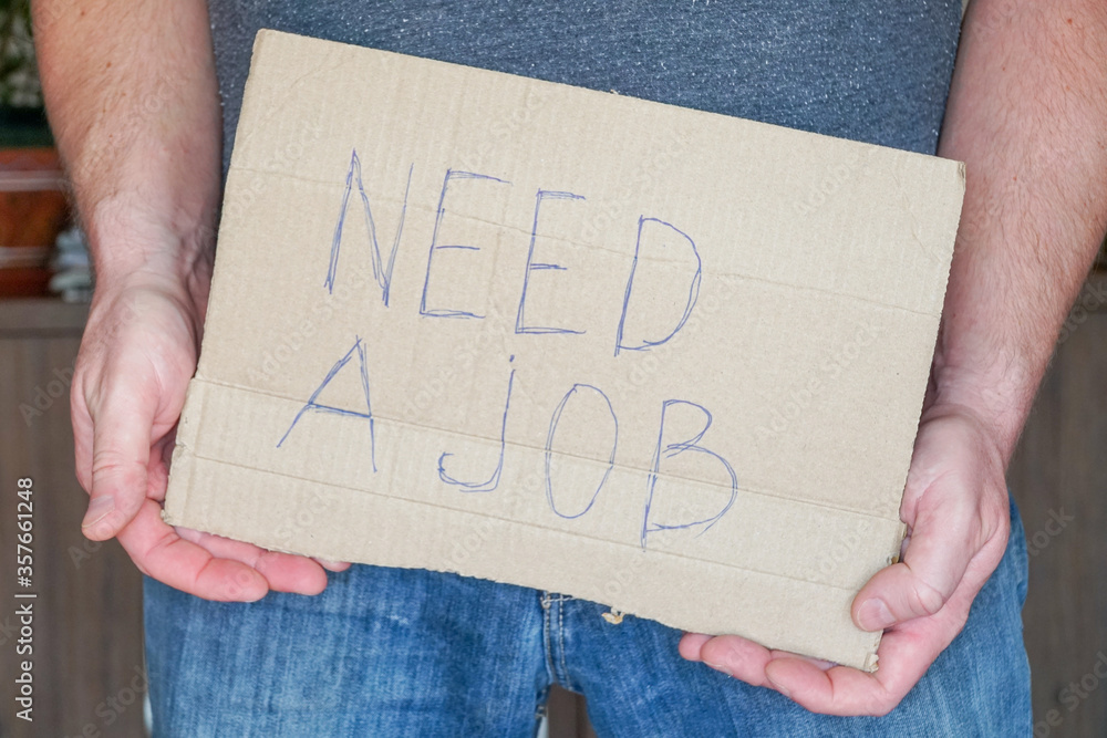 Man in jeans holds a cardboard in his hands search a job