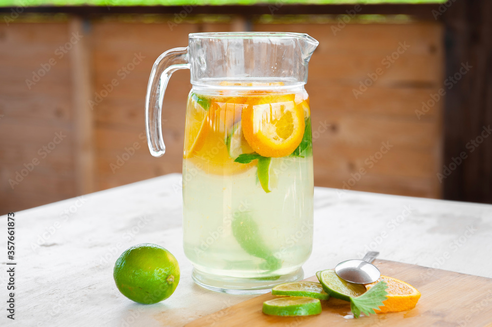 Fototapeta premium lime, mint and orange lemonade,on an old wooden table, a refreshing drink in the hot summer. Cooling, pleasant taste. Ingredients, homemade recipe