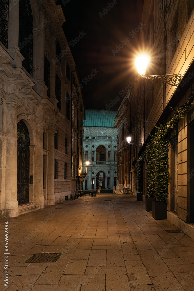 Night view of the street called Contra Monte in the historic center of Vicenza. In the background is the Palladian Basilica of Andrea Palladio with the light green oxidized copper roof. Italy.