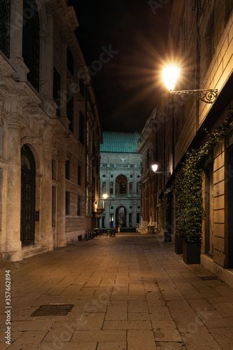 Night view of the street called Contra Monte in the historic center of Vicenza. In the background is the Palladian Basilica of Andrea Palladio with the light green oxidized copper roof. Italy.