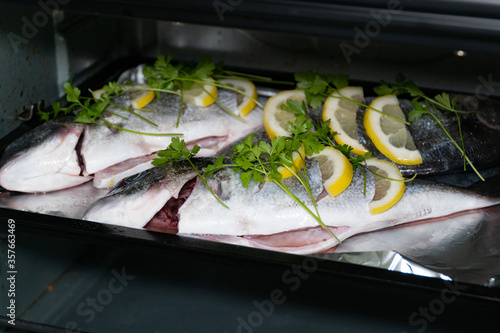 Obraz na płótnie Fresh dorada fish with lemon and parsley on a baking sheet in the oven. w salonie