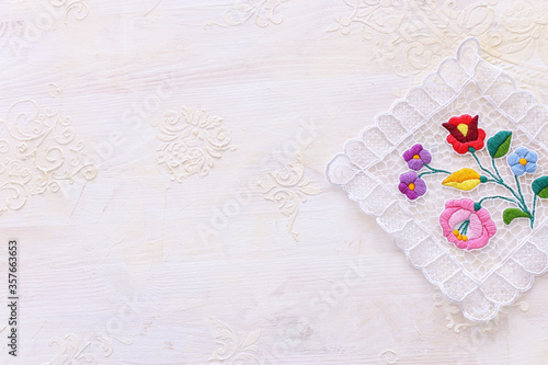 top view of floral tablecloth with over white wooden background © tomertu