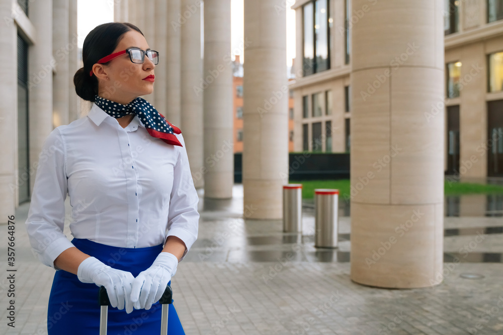 Portrait of a stylish smiling stewardess in a blue skirt with a white blouse. Mysterious girl in a business suit looks away Portrait of a stylish smiling stewardess in a blue skirt with a white blouse. Mysterious girl in a business suit looks away