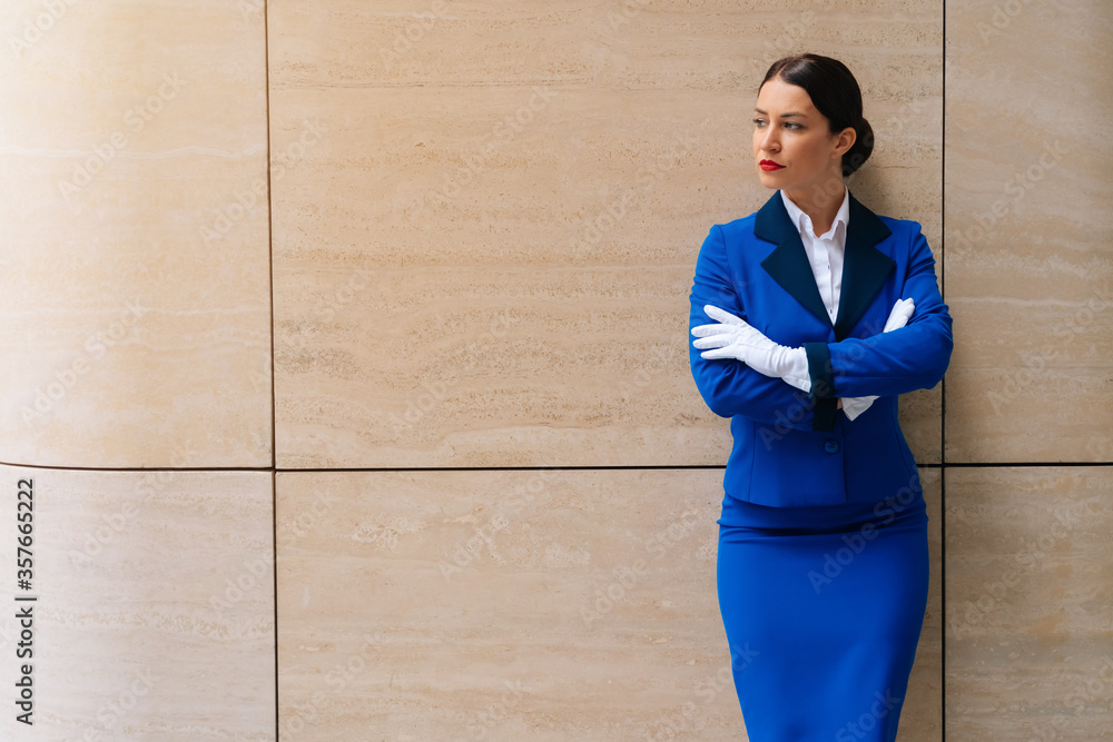 Elegant stewardess points to the side for copy space with her own hands. A flight attendant in a