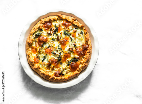 Canned tuna  mozzarella  spinach  potatoes rustic pie on a light background  top view