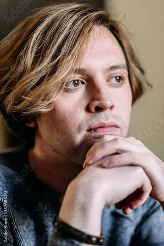 Handsome young man with blond hair looks thoughtfully to the side, dreams and goals in his thoughts, pensive and dreamy shot