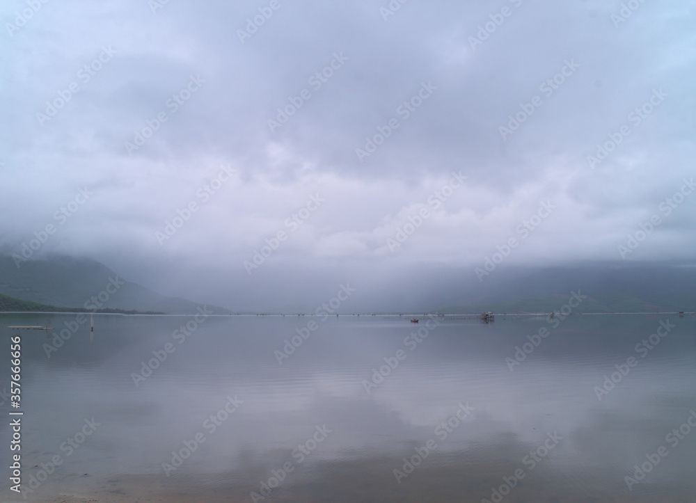 Tief hängende Wolken über einem spiegelglatten See