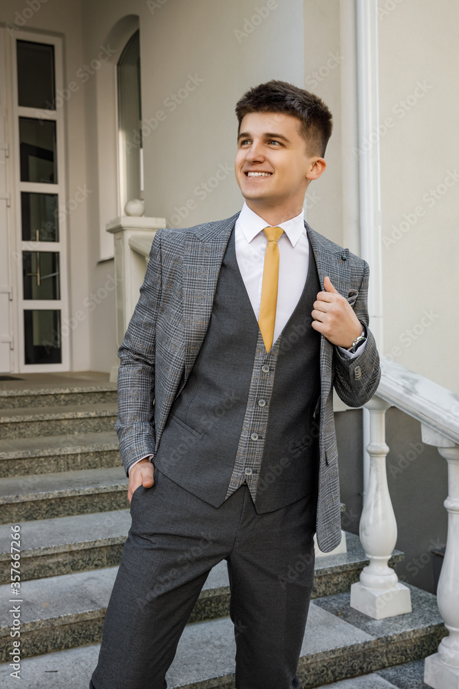 Handsome young man in formal wear looking away and adjusting jacket while standing against gray background. Smiling and looking aside
Handsome young man in formal wear looking away and adjusting jacket while standing against gray background. Smiling and looking aside