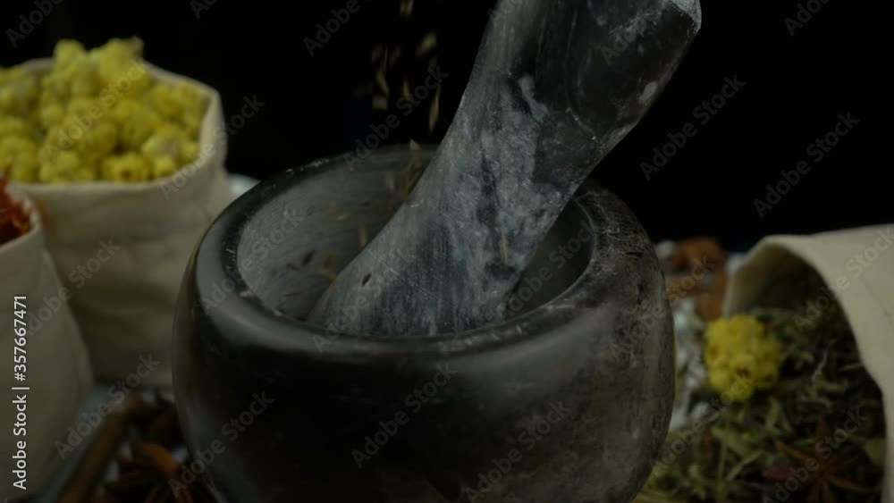 Cumin seeds falling into the granite mortar with pestle in slow motion. Healthy and organic food, herb medicine, natural care, aromatherapy and organic cosmetics concept. Cumin seeds falling into the granite mortar with pestle in slow motion. Healthy and organic food, herb medicine, natural care, aromatherapy and organic cosmetics concept.