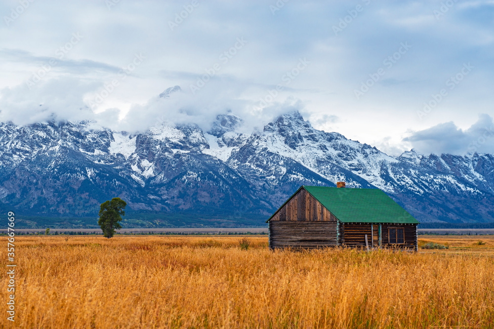 Grand Teton Range Peaks in the first snow and mist in autumn with a building of the T. A. Moulton barn inside Grand Teton National Park, Wyoming,United States of America (USA).