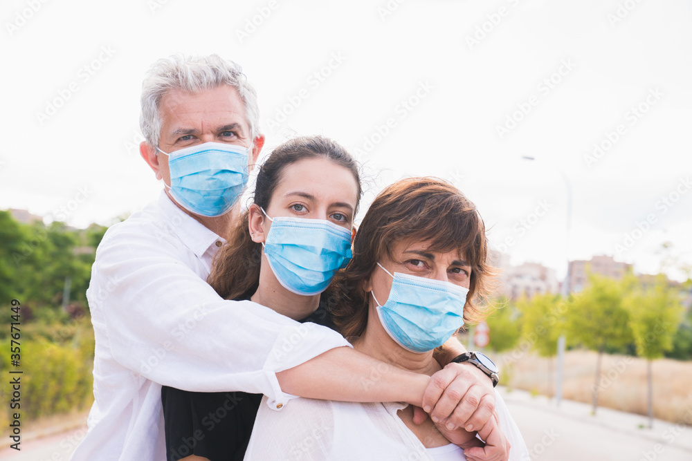 New normal. Masked family hugs. Members of a family hug each other with protective masks. Family protected with masks against coronavirus. Safety and pandemic concept. Coronavirus. Social distance.