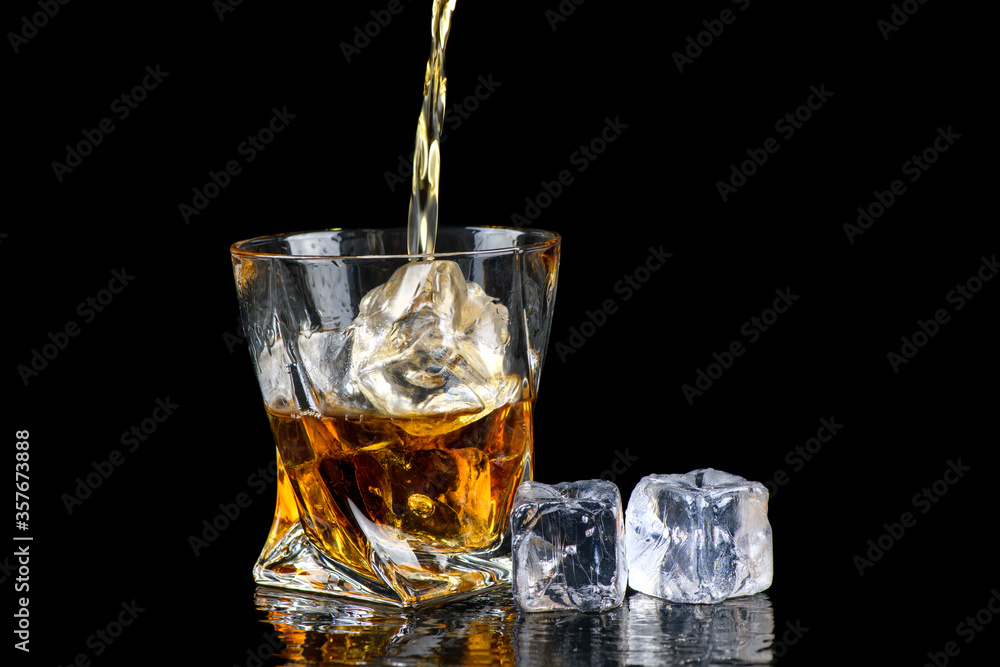 Glass of whiskey with cube ice on black background Glass of whiskey with cube ice on black background