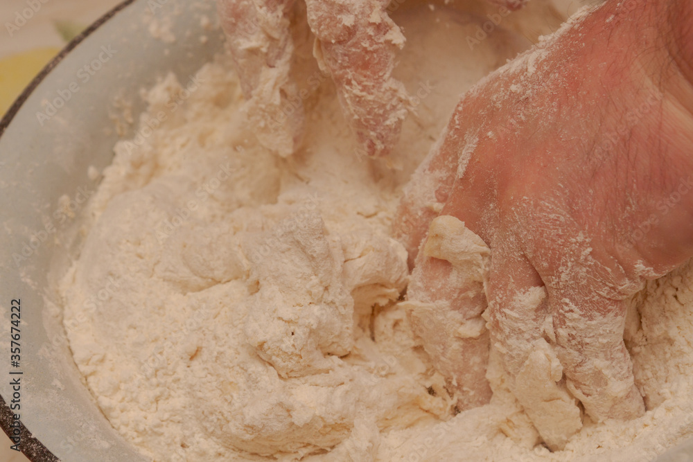 Fototapeta premium Cooking dough in a white metal bowl at home