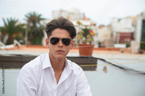 Fotografi Portrait of young man with aviator glasses on rooftop.