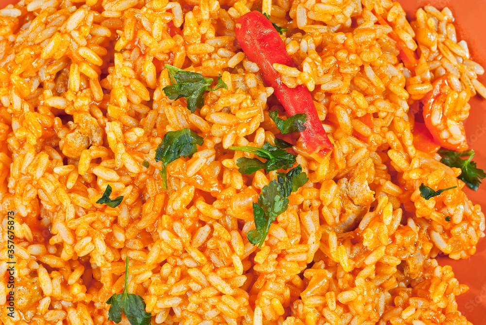 Pilaf with meat, cucumbers, greens and carrots in an orange plate. Pilaf with meat, cucumbers, greens and carrots in an orange plate.