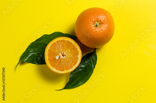 Fototapeta Naklejka Na Ścianę i Meble -  a whole orange and half an orange, and two green leaves