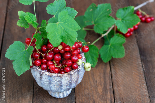 Ripe red currants with leaves, wooden table