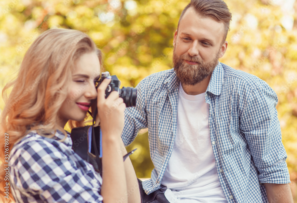 Fototapeta premium Man and woman having date outdoor. Girl wit a photo camera and her boyfriend.