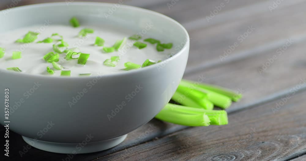 Sour cream with chopped green onion in bowl rotates slowly. Sour cream with chopped green onion in bowl rotates slowly.