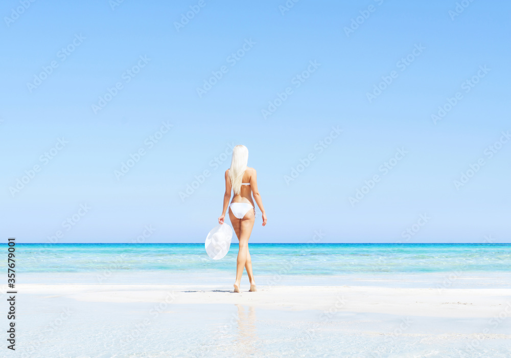 Young and beautiful blond woman posing in bikini on the beach. Fit and sexy fashion model in swimsuit. Young and beautiful blond woman posing in bikini on the beach. Fit and sexy fashion model in swimsuit.