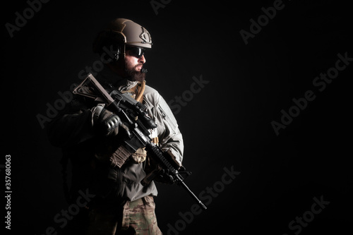Fotografie portrait of a special forces soldier in uniform with a weapon against a dark bac