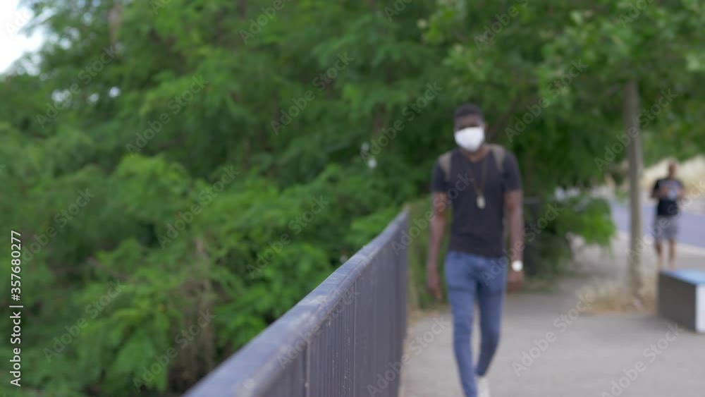 black man with mask on the bridge leaning against the balustrade looking away black man with mask on the bridge leaning against the balustrade looking away