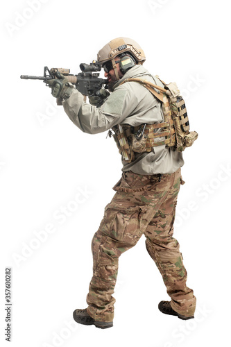 American ranger in military equipment and with a rifle aiming and shoots on a white background, portrait of a special forces soldier with weapons