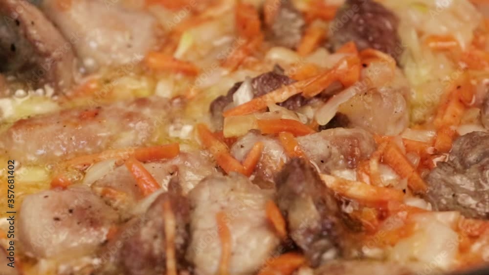 Pieces of meat and carrots are fried in a pan. Close-up. Pieces of meat and carrots are fried in a pan. Close-up.