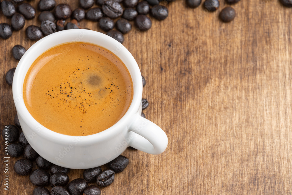 Aerial view of white cup with coffee on wooden table with coffee beans, horizontal, with copy space Aerial view of white cup with coffee on wooden table with coffee beans, horizontal, with copy space