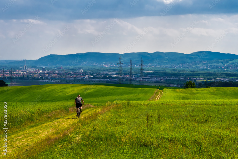 Man Rides Mountainbike In Rural Landscape In Front Of Skyline Of Vienna In Austria