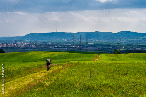 Man Rides Mountainbike In Rural Landscape In Front Of Skyline Of Vienna In Austria